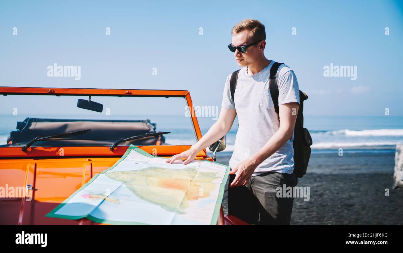 Homme avec carte près de la voiture sur la plage Banque D'Images