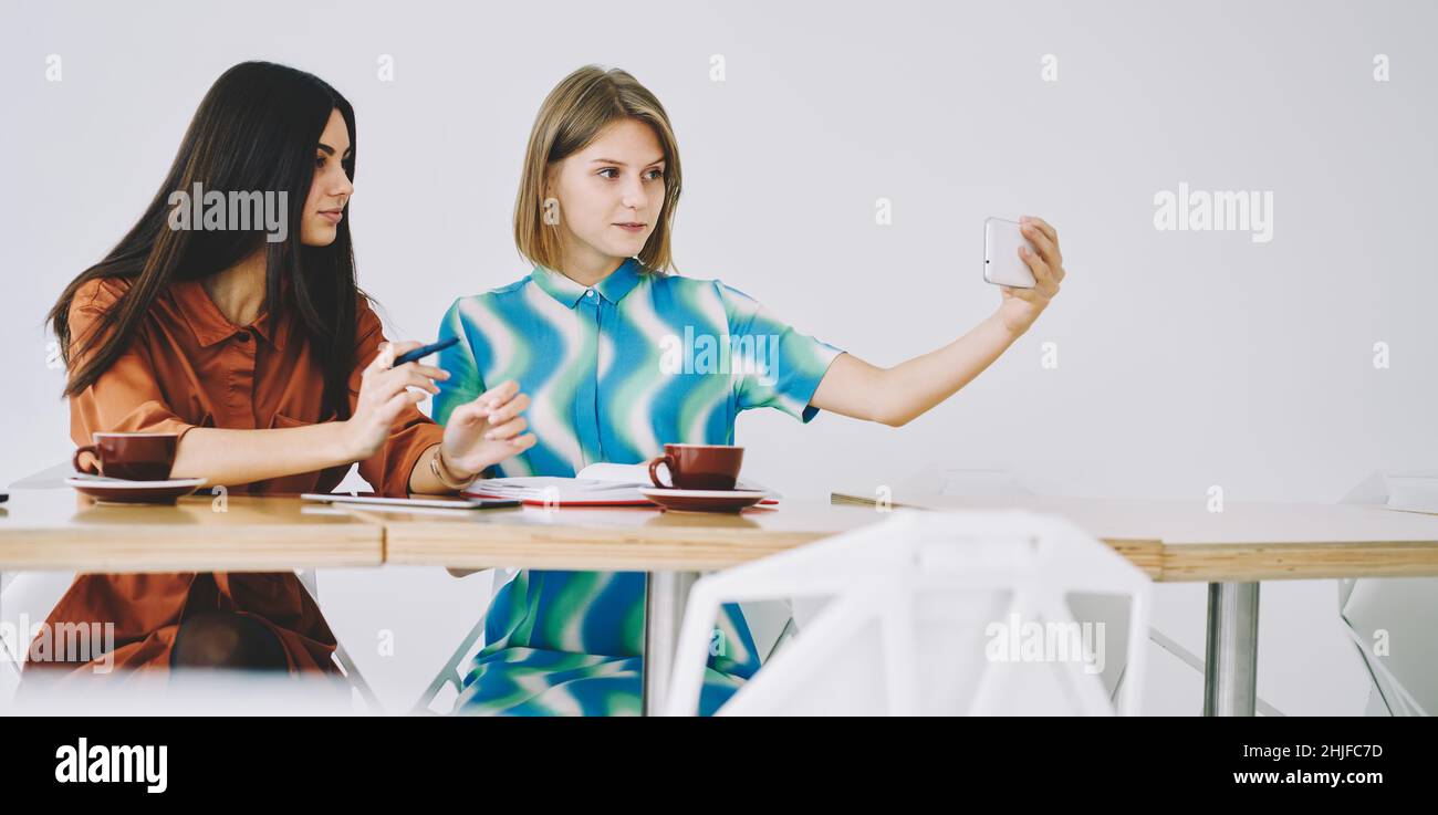 Des amies gaies parlent selfie contre un mur blanc Banque D'Images