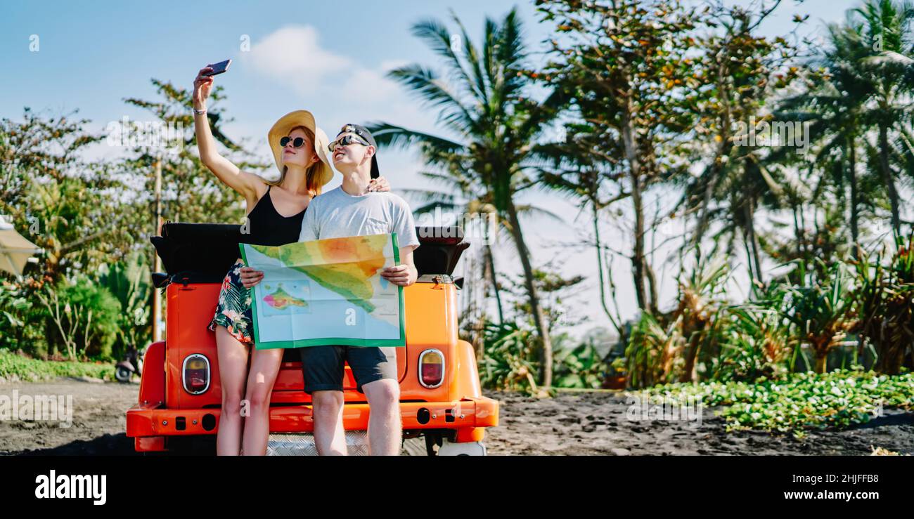 Couple insouciant prenant le selfie debout avec la carte Banque D'Images