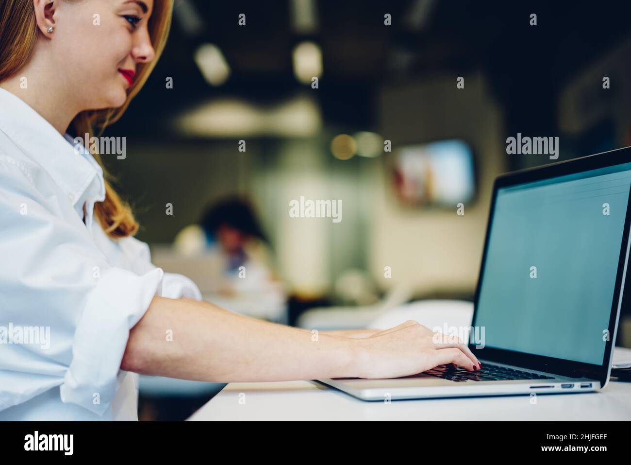 Jeune femme qui tape sur un ordinateur portable tout en travaillant Banque D'Images