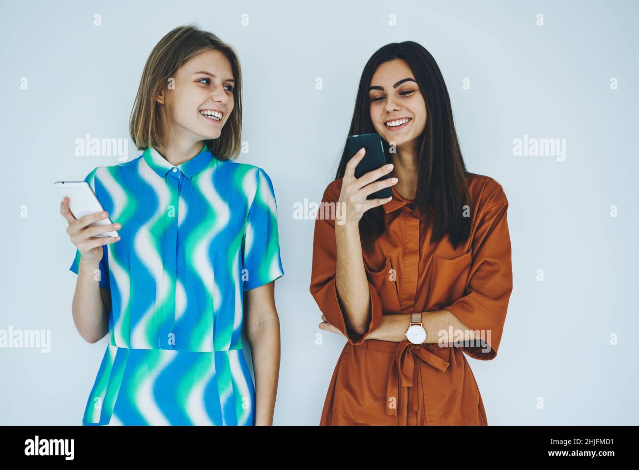 Des femmes heureuses utilisant des téléphones portables debout Banque D'Images