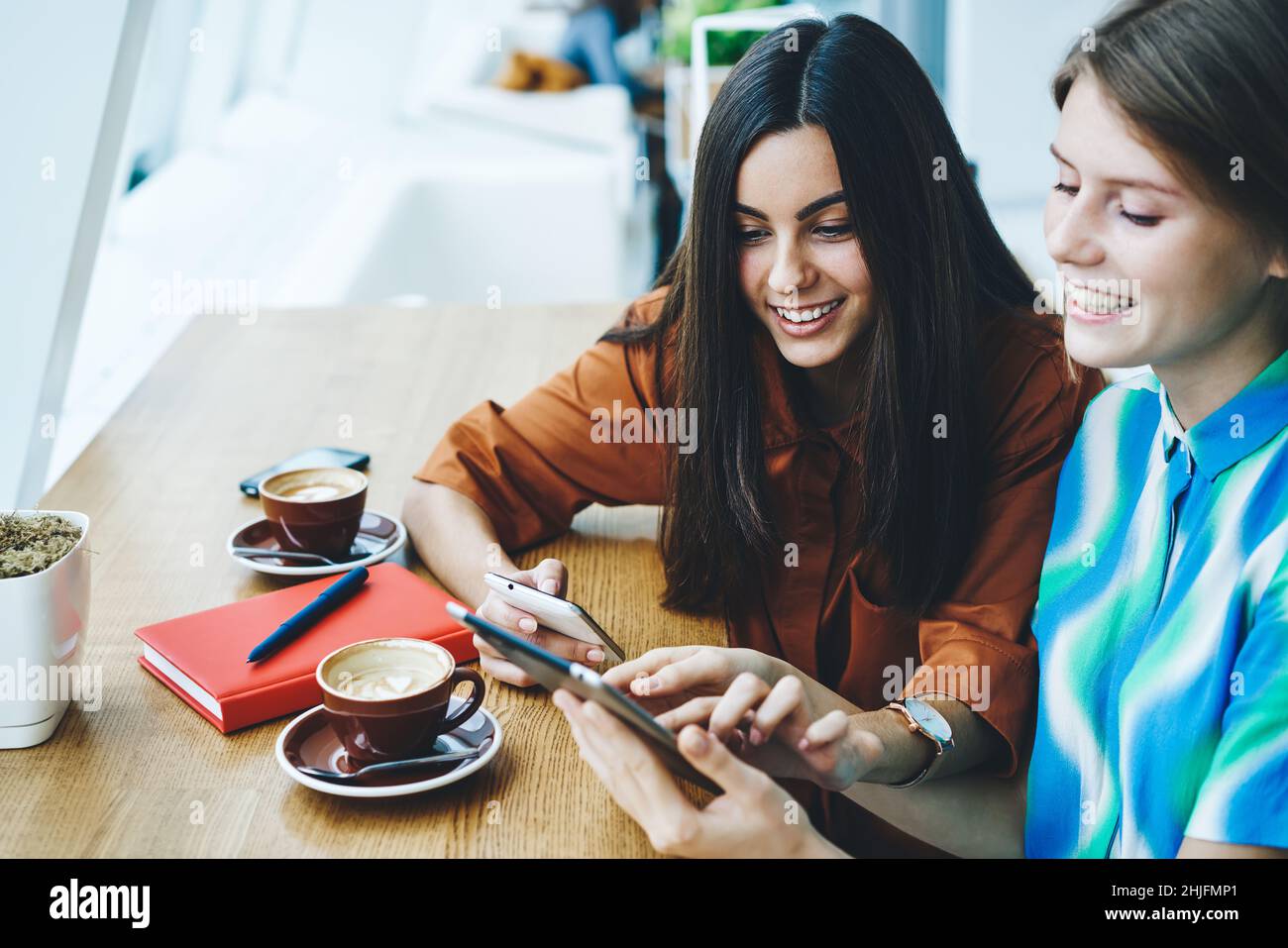 Femmes utilisant une tablette et un smartphone dans un café Banque D'Images