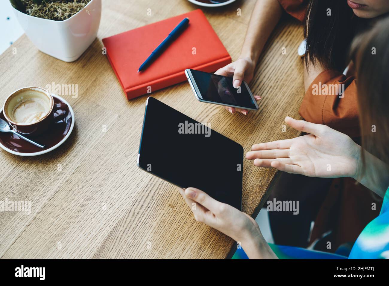 Femmes méconnues utilisant une tablette et un smartphone dans un café Banque D'Images