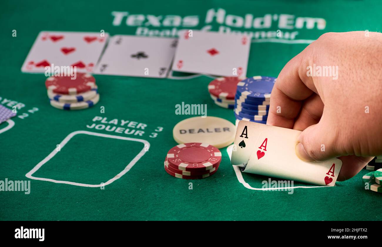 mains d'un homme montrant une paire d'as et de jetons de poker. Banque D'Images