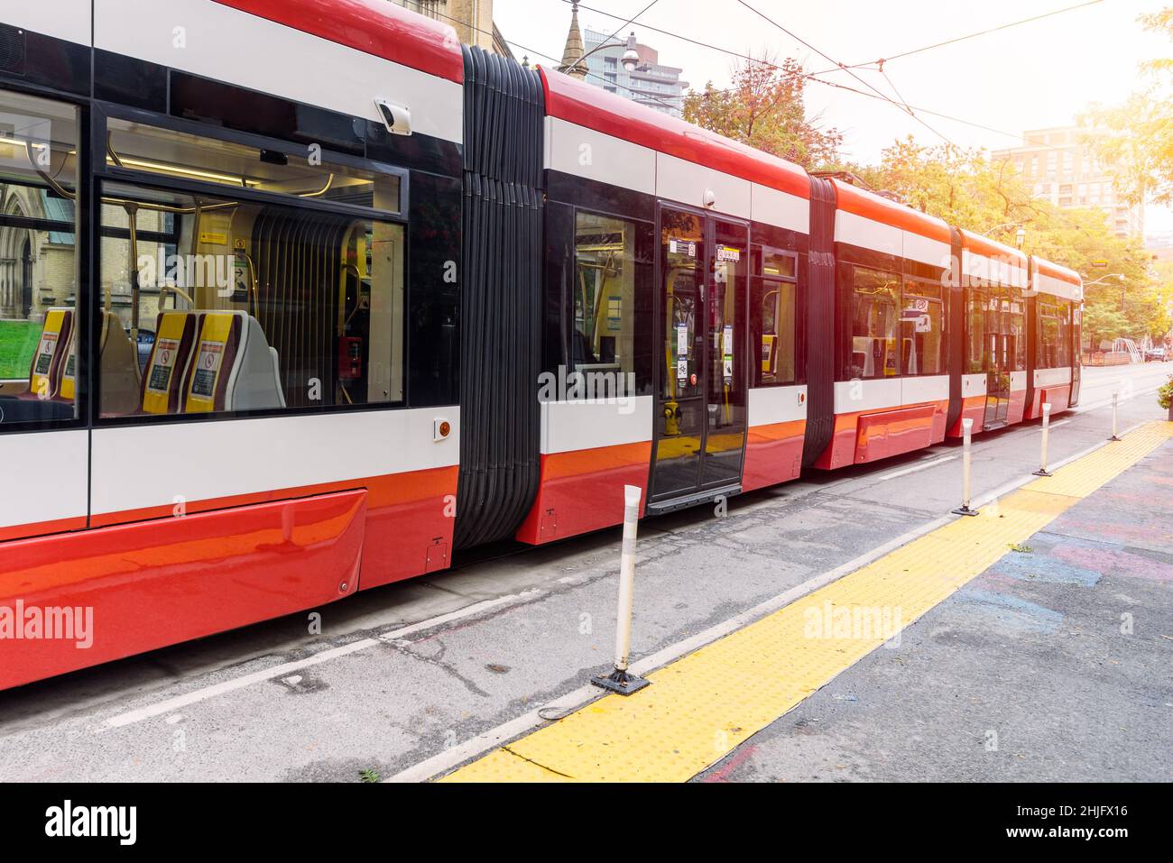 Tram laissant un arrêt le long d'une rue dans un centre-ville lors d'une journée d'automne ensoleillée Banque D'Images