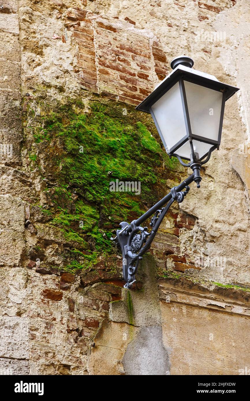 Une célèbre lanterne de rue sur un vieux mur avec de la mousse verte à Asciano, province de Sienne Banque D'Images