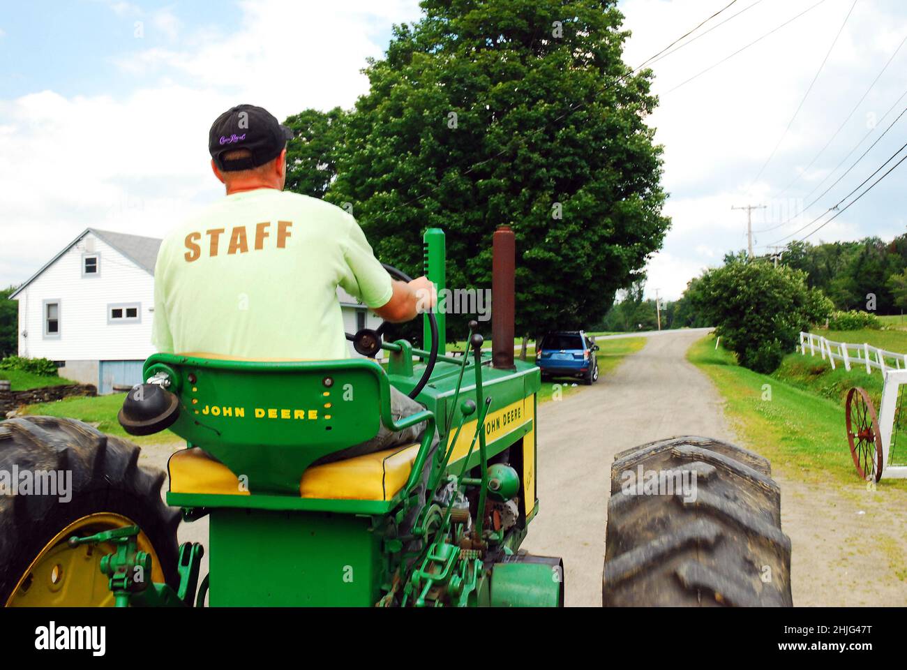 Un jeune homme conduit son tracteur autour de la ferme Banque D'Images