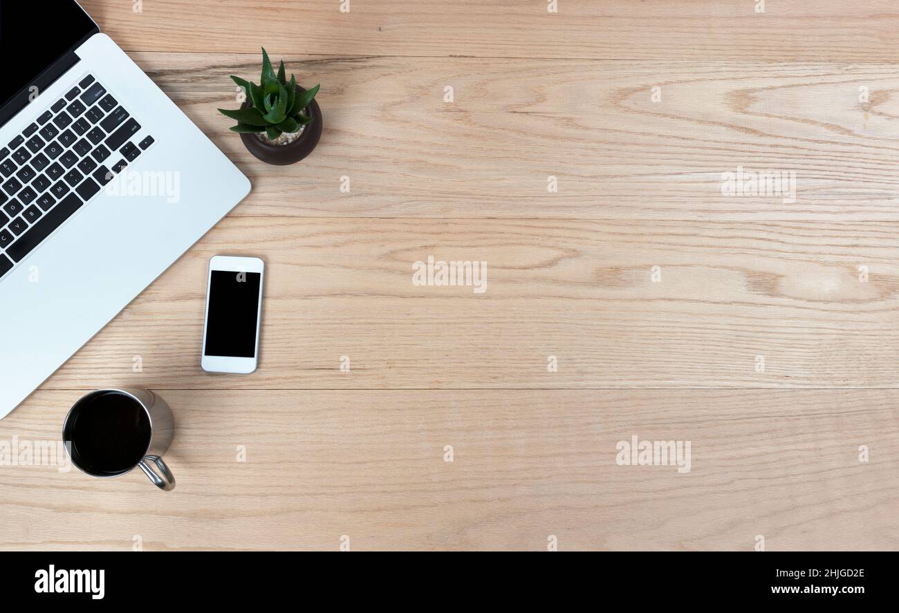 Bureau en chêne bureau table avec ordinateur portable, smartphone, plante pour bébé et café pour le travail ou l'école.Vue de dessus avec espace de copie sous forme de mise en page à plat Banque D'Images