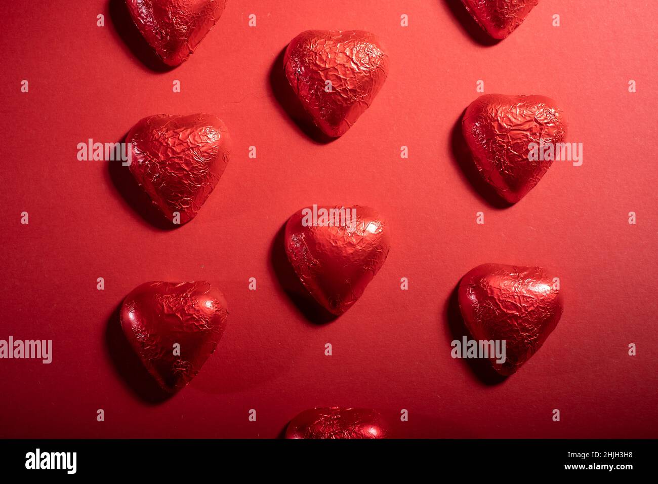 Helsinki / Finlande - 29 JANVIER 2022 : gros plan des confiseries au chocolat en forme de cœur et des roses rouges sur fond rouge vif. Banque D'Images