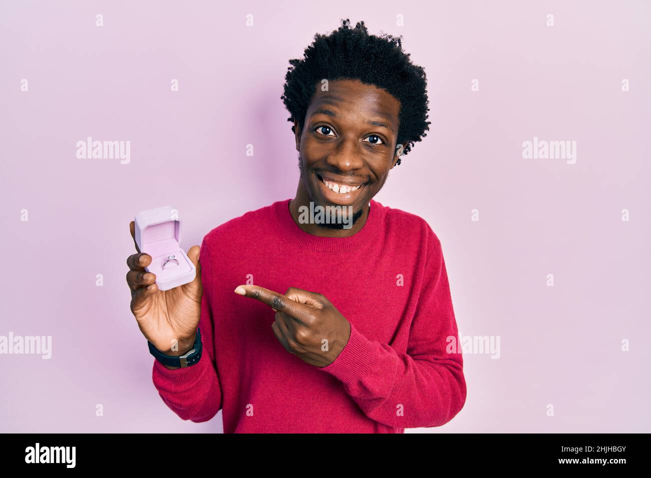 Un jeune afro-américain qui tient un cercle d'engagement pour la proposition souriant se réjouit de pointer du doigt et de la main Banque D'Images