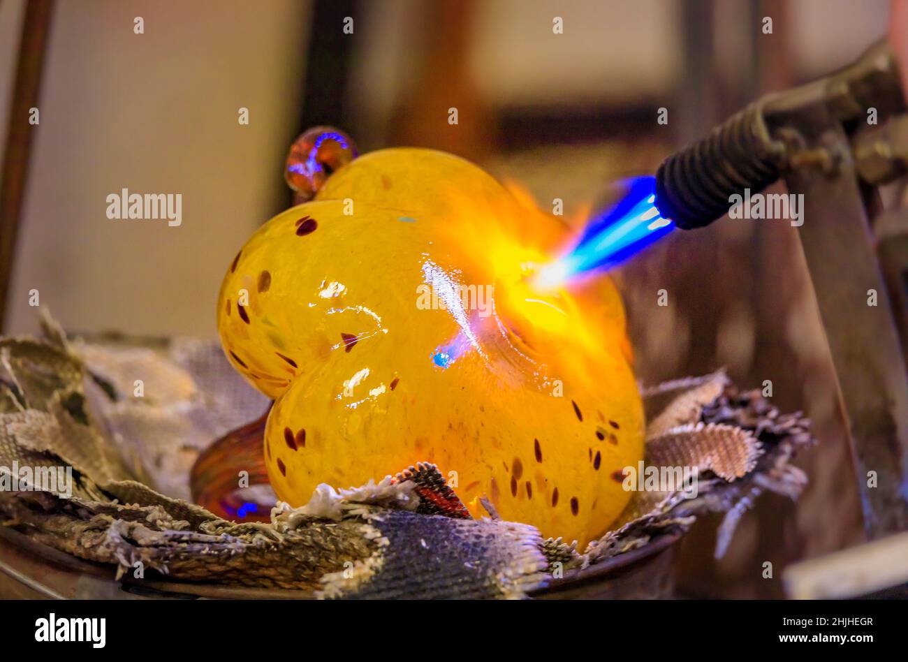 Souffleur de verre façonnant une bulle de verre fondu avec une torche de soufflage dans le processus de fabrication dans un atelier de fabrication de verre, faible profondeur de champ Banque D'Images
