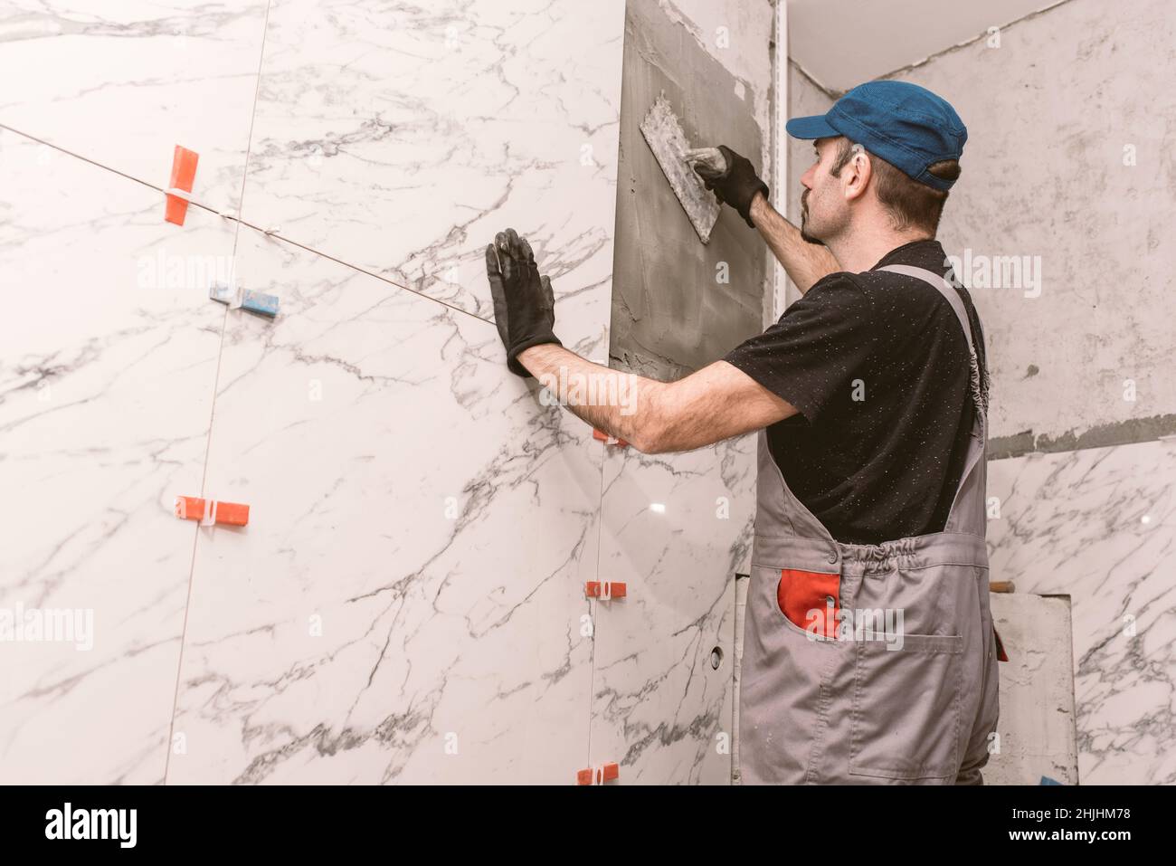Le handyman pose des carreaux de céramique sur le mur de la salle de bains Banque D'Images