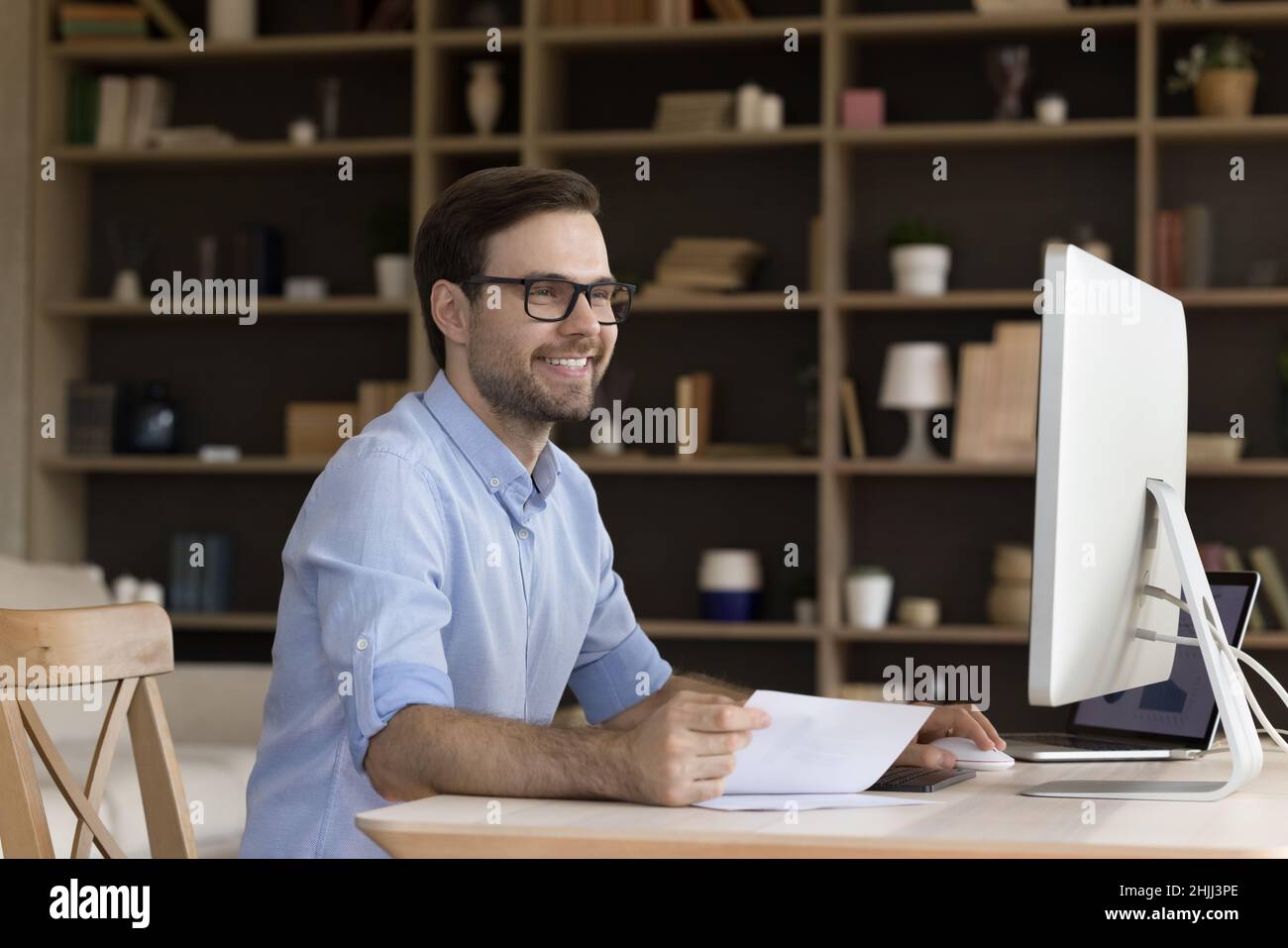 Souriant, beau employé du millénaire travaillant au bureau à domicile. Banque D'Images