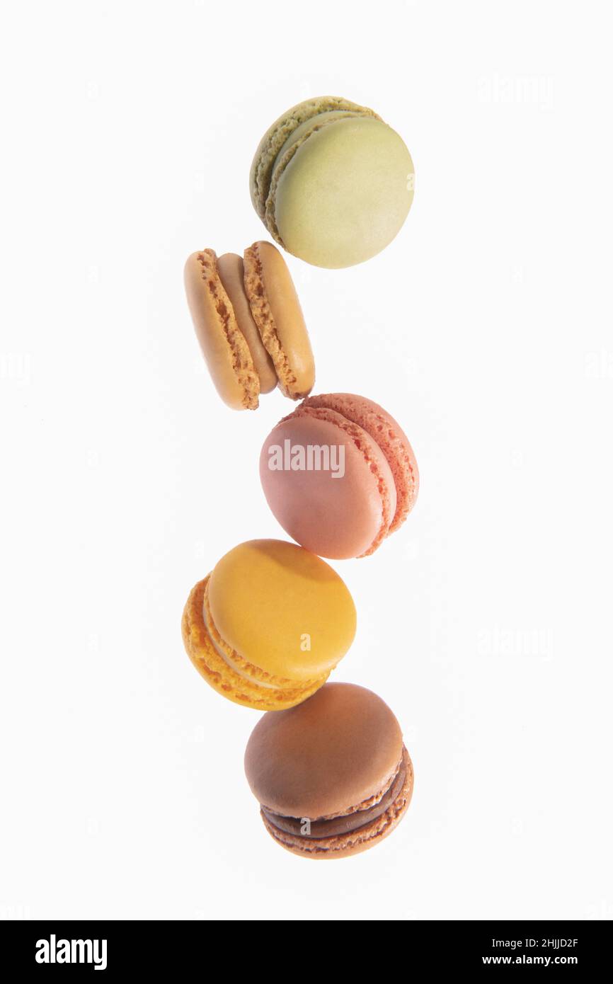 Macarons colorés tombant sur un fond clair Banque D'Images