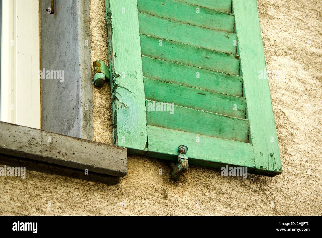 Maison en pierre avec volet de fenêtre vert et support de volet. Banque D'Images