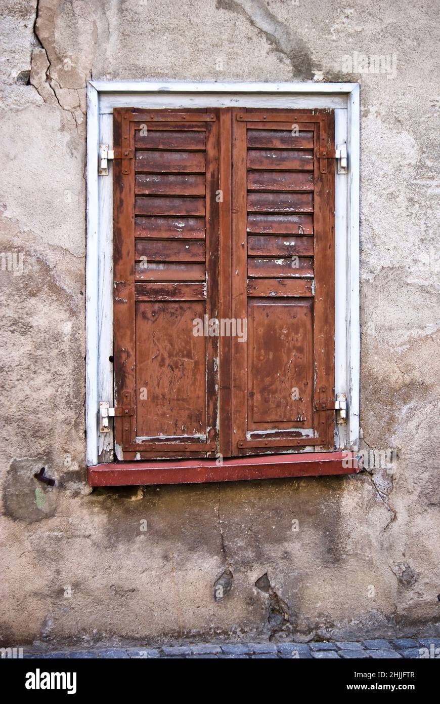 Vieux mur en pierre avec fenêtre et volets de fenêtre bruns en Suisse. Banque D'Images