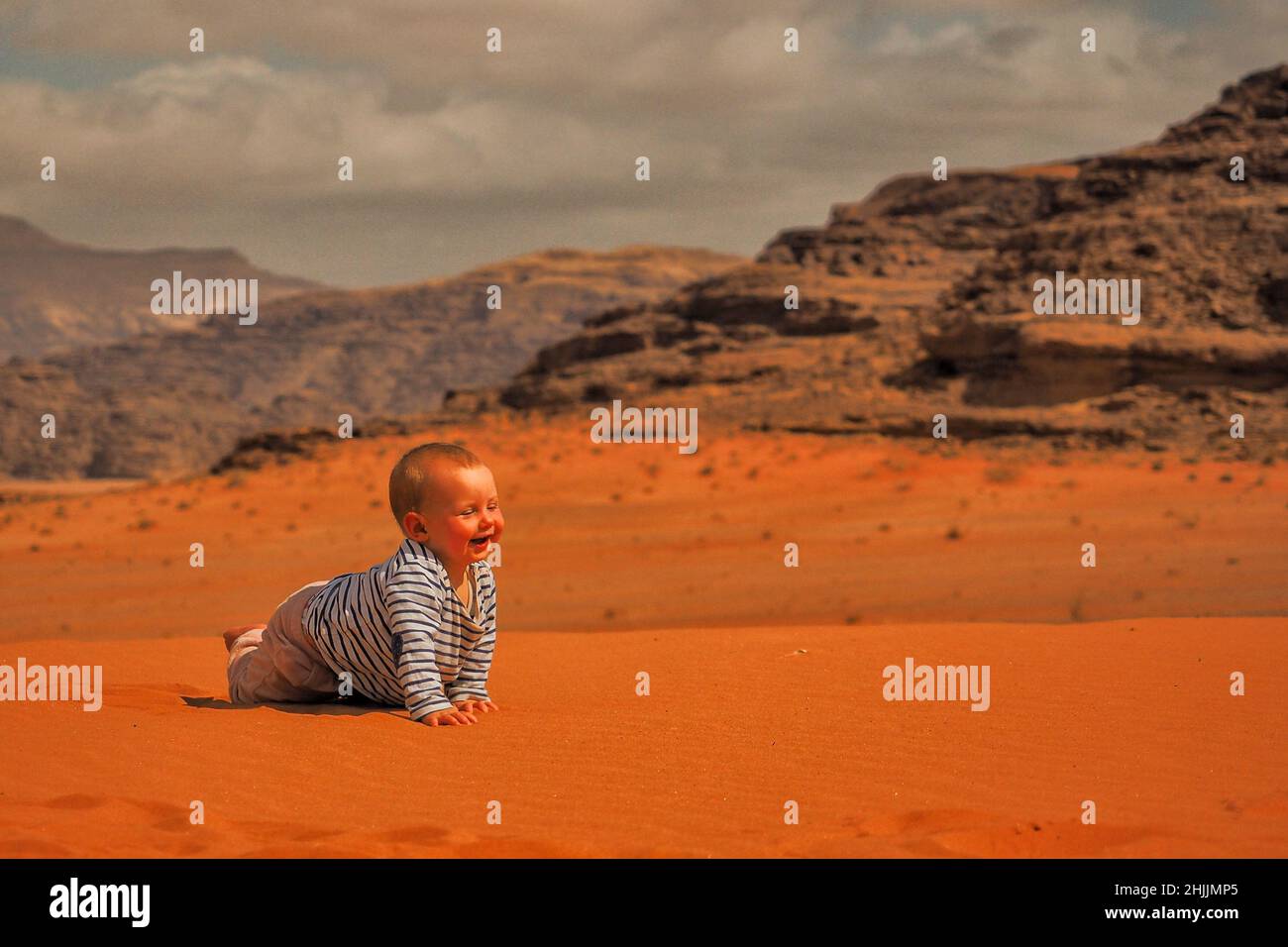 Une petite fille mignonne rampant sur un sable.Désert et montagnes de Wadi Rum, Jordanie. Banque D'Images