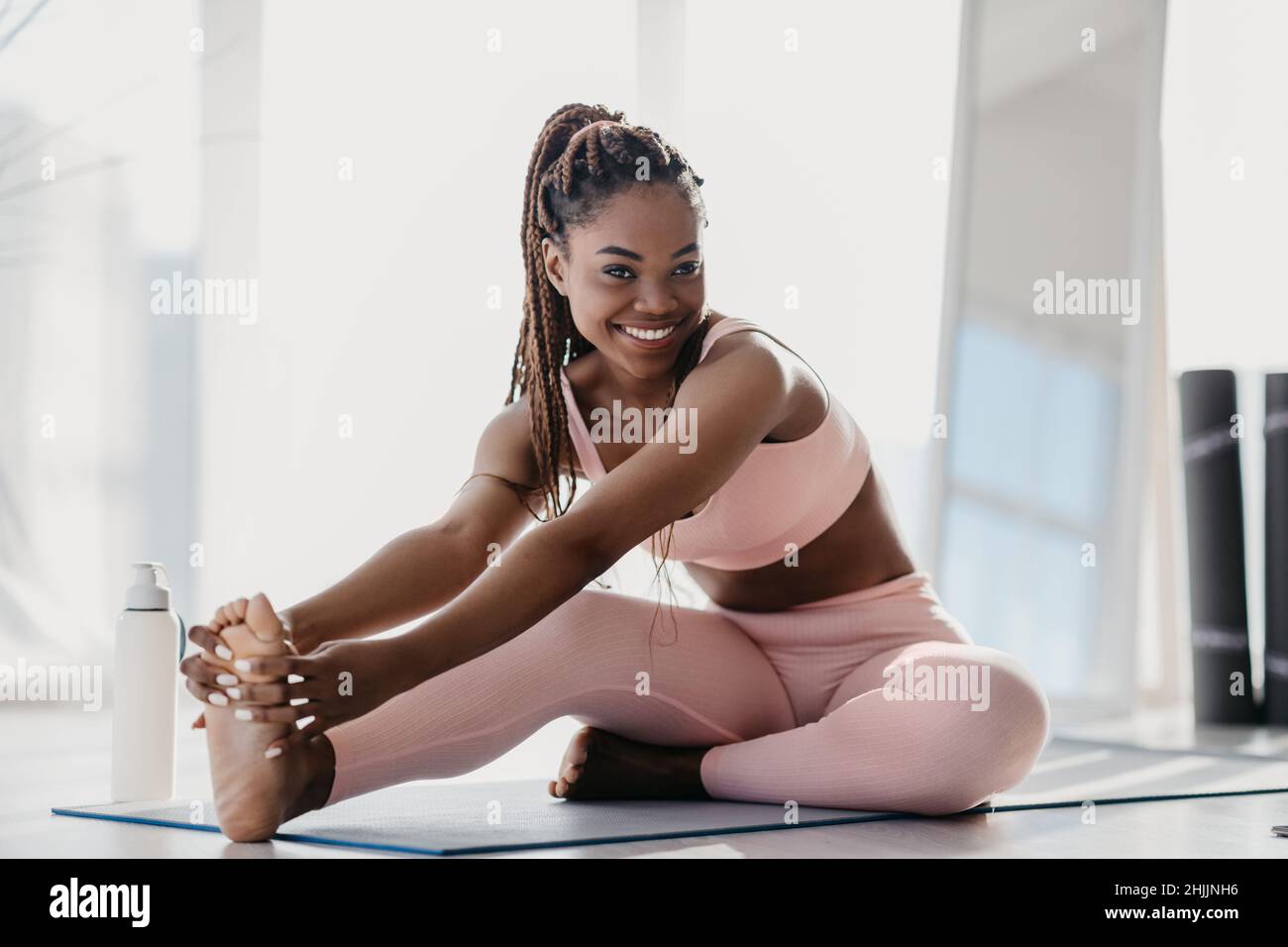 Bonne sportive jeune femme noire en vêtements de sport étirant son corps à la maison, sur toute la longueur Banque D'Images