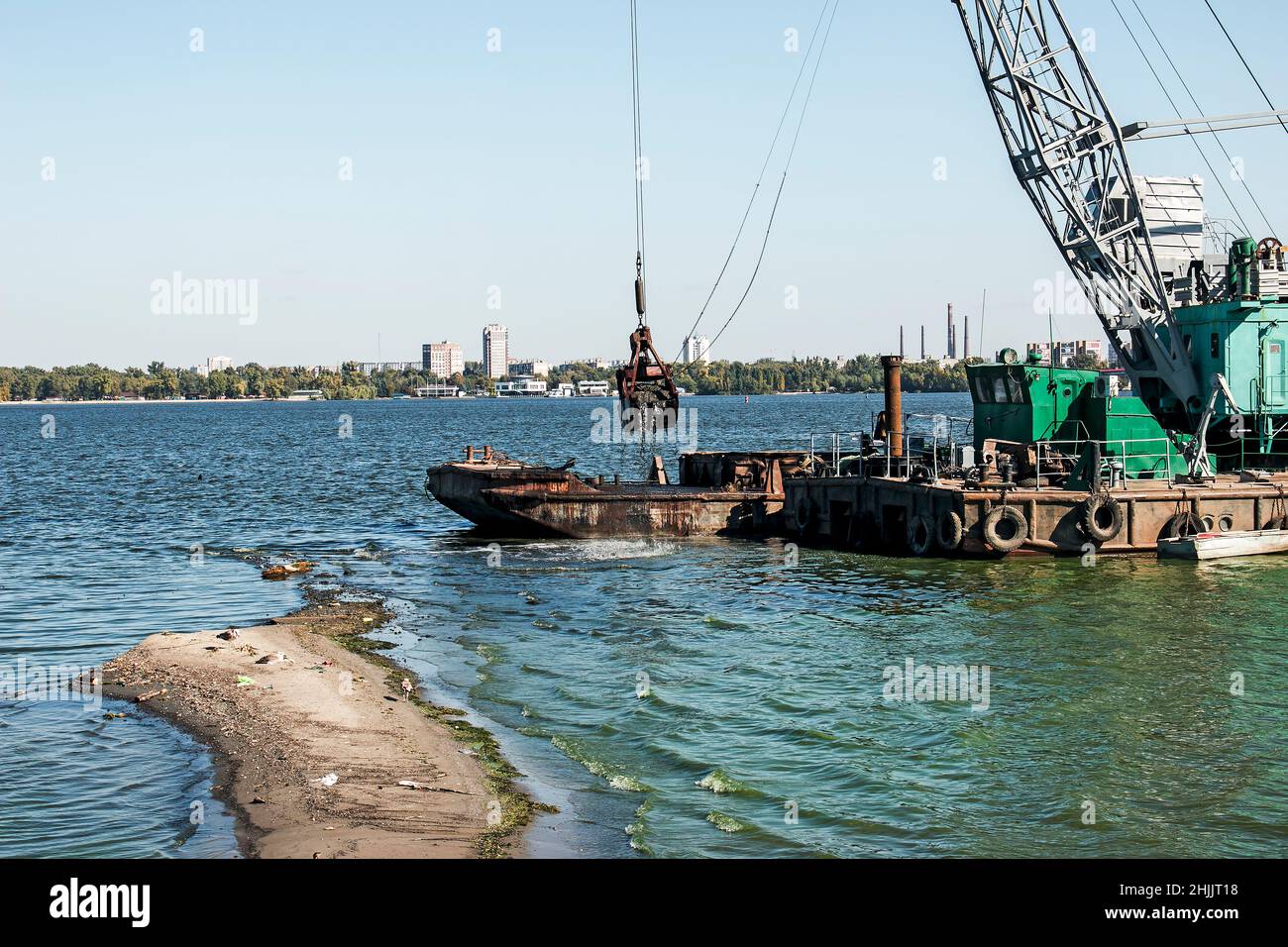 Nettoyage de l'île nouvellement formée des déchets industriels sur la rivière Dniepr par un dragueur.Problèmes environnementaux des rivières modernes.Concept d'écologie. Banque D'Images