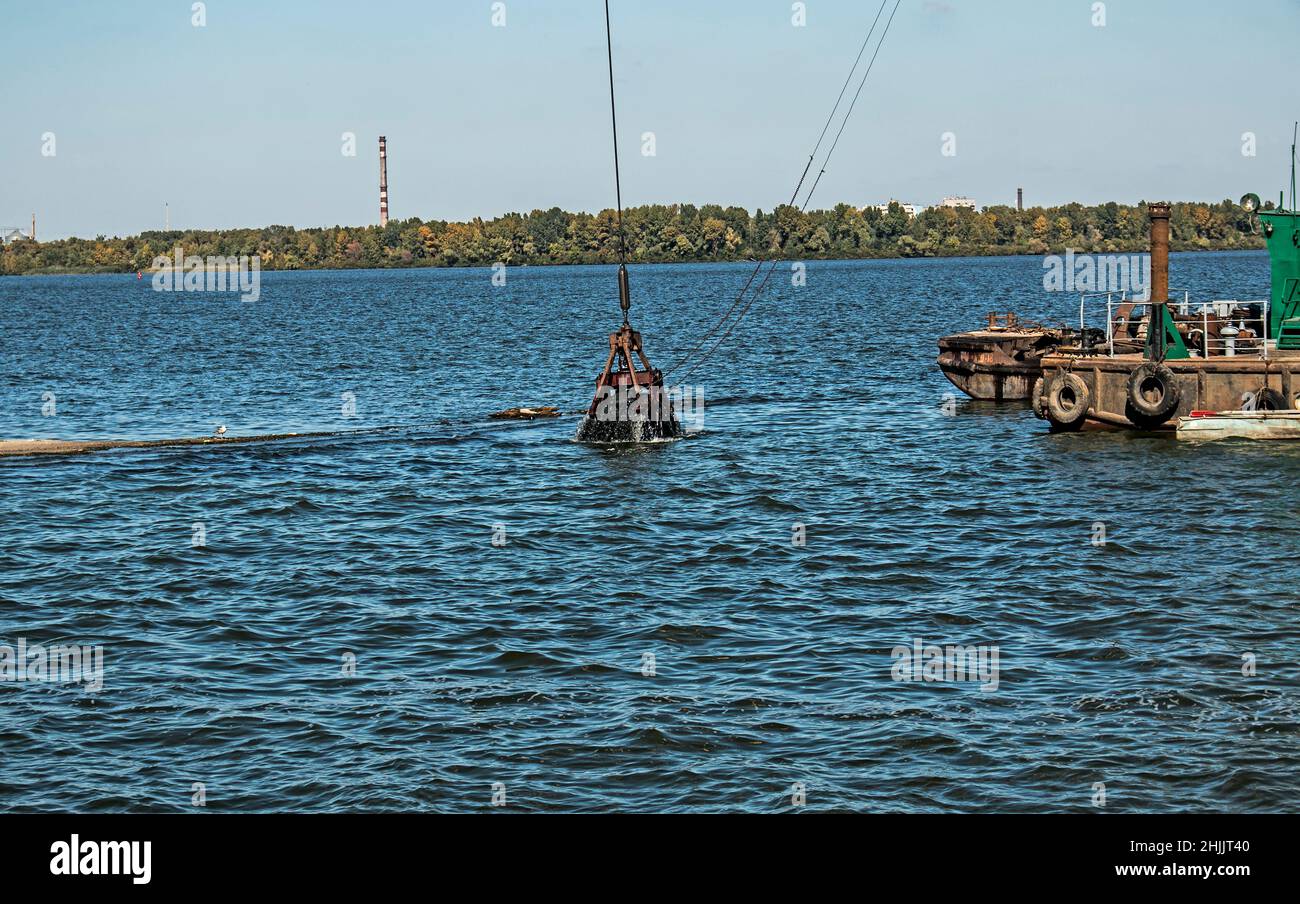 Nettoyage de l'île nouvellement formée des déchets industriels sur la rivière Dniepr par un dragueur.Problèmes environnementaux des rivières modernes.Concept d'écologie. Banque D'Images