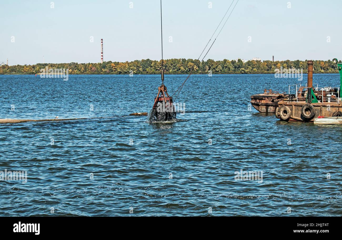 Nettoyage de l'île nouvellement formée des déchets industriels sur la rivière Dniepr par un dragueur.Problèmes environnementaux des rivières modernes.Concept d'écologie. Banque D'Images