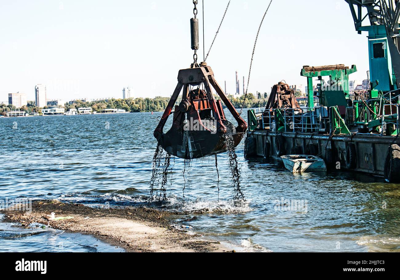 Nettoyage de l'île nouvellement formée des déchets industriels sur la rivière Dniepr par un dragueur.Problèmes environnementaux des rivières modernes.Concept d'écologie. Banque D'Images