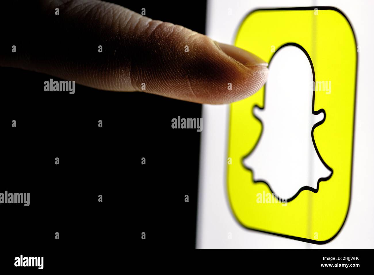 Le doigt atteint le logo du service de messagerie instantanée Snapchat sur l'écran du smartphone. Banque D'Images