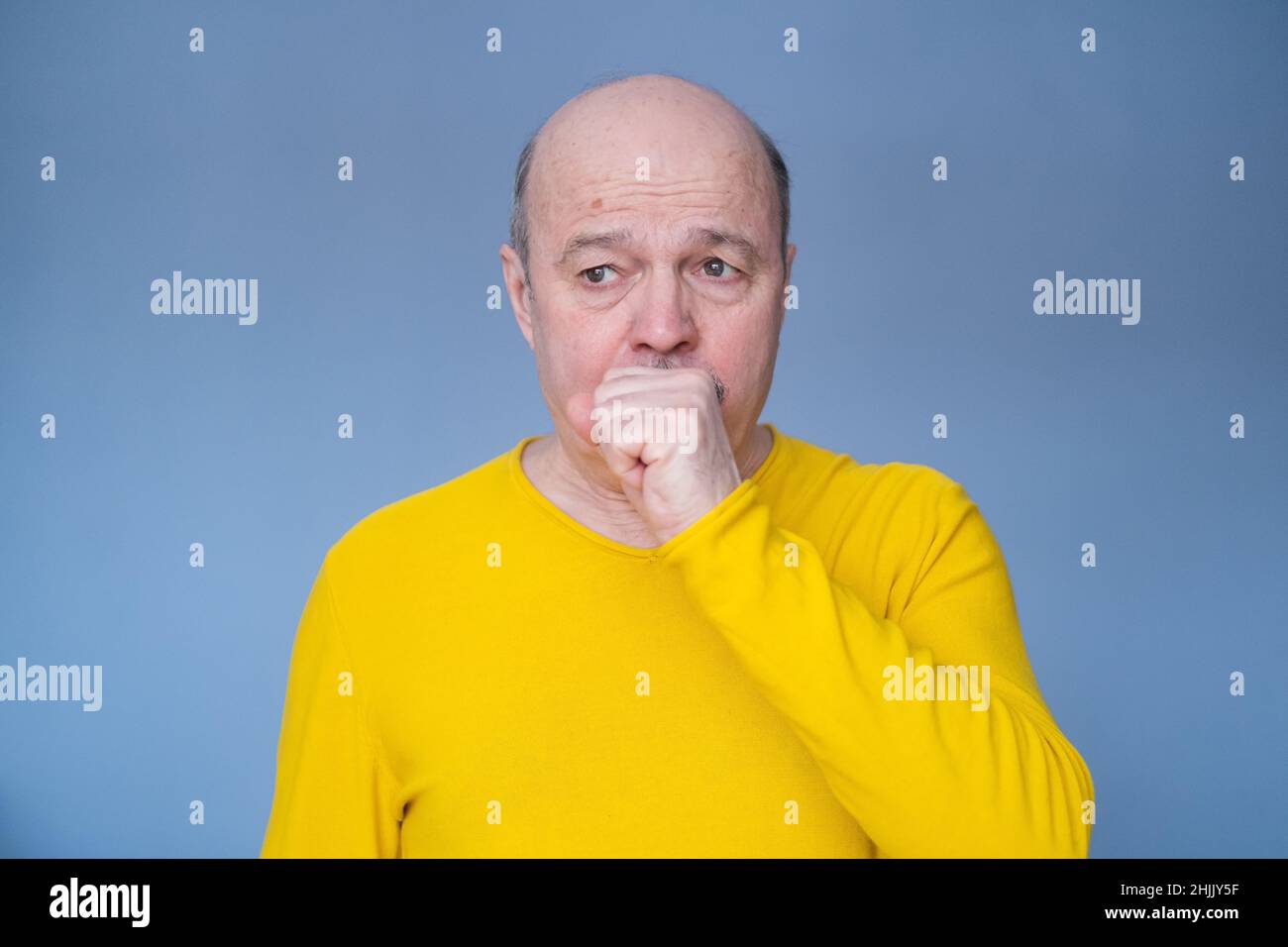 La toux de monsieur hispanique âgé est due à une maladie pulmonaire isolée sur fond bleu Banque D'Images