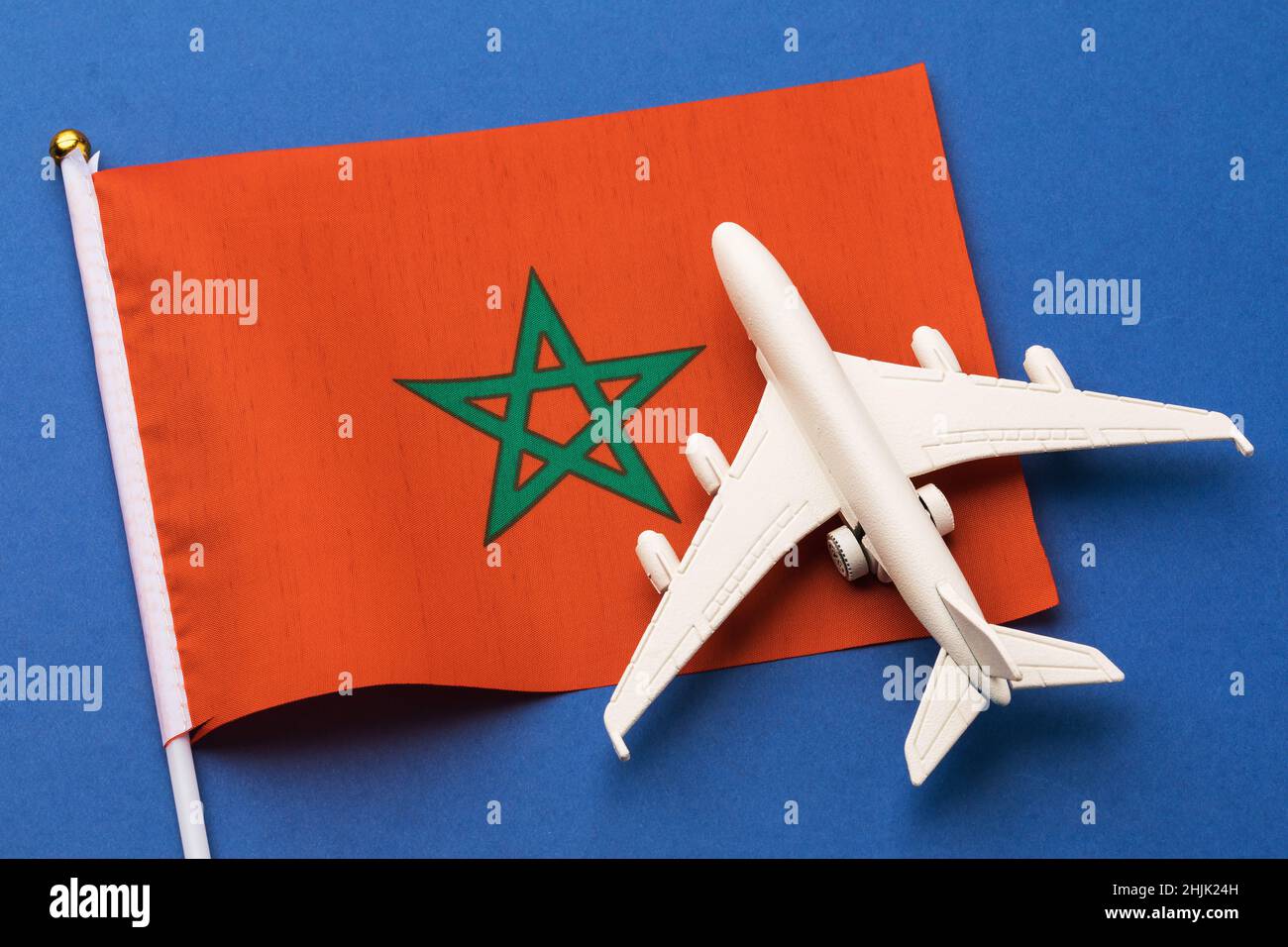 Drapeau Marocan et avion jouet sur fond bleu, concept de vol pour le Maroc, vue de dessus Banque D'Images