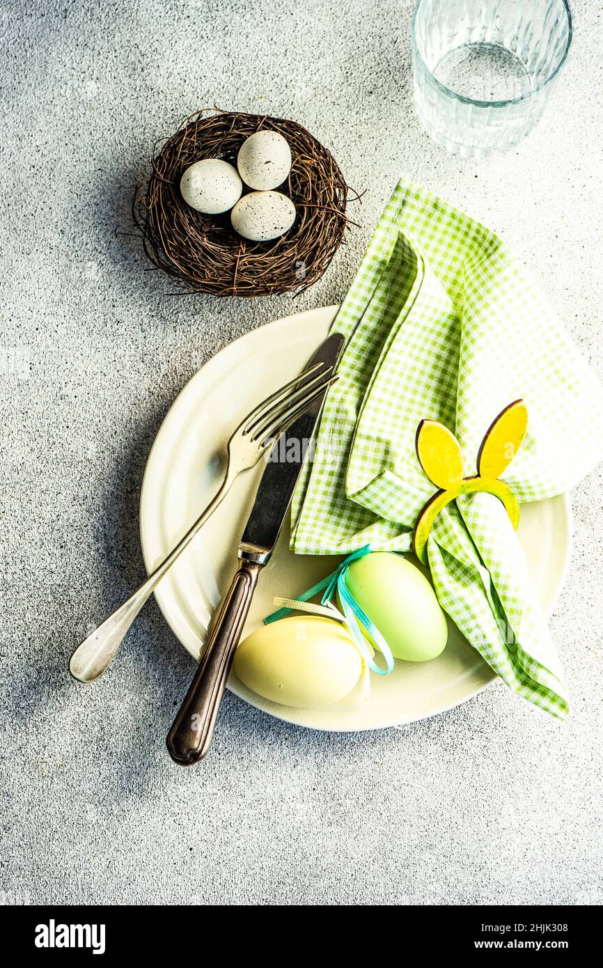 Vue en hauteur d'un endroit avec des œufs de Pâques dans un nid sur une table et un verre d'eau Banque D'Images
