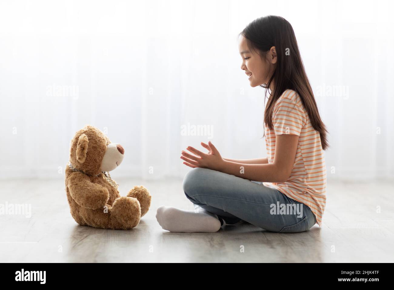 Enfant chinois assis sur le sol avec son ours en peluche Banque D'Images