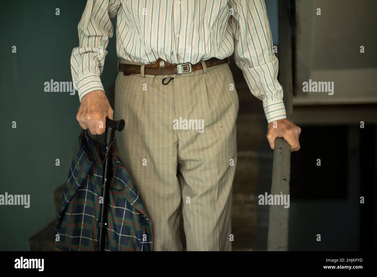Le pensionné descend les escaliers.Grandpa descend les marches.Vieil homme en Russie.La main se tient sur la main courante. Banque D'Images