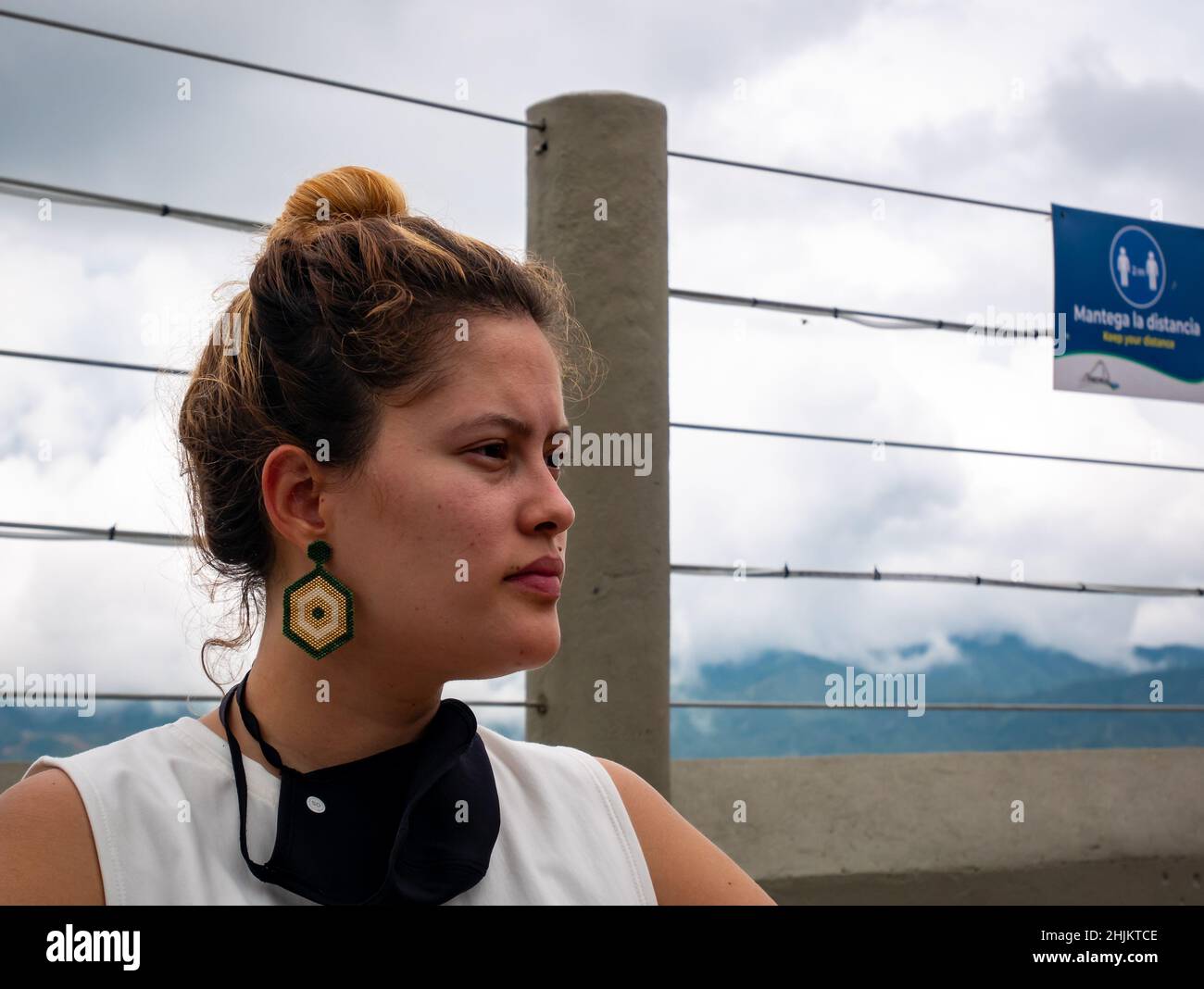 Guatape, Antioquia, Colombie - décembre 8 2021 : la femme colombienne aux cheveux teints et aux grandes boucles d'oreilles a un masque noir sur son cou Banque D'Images