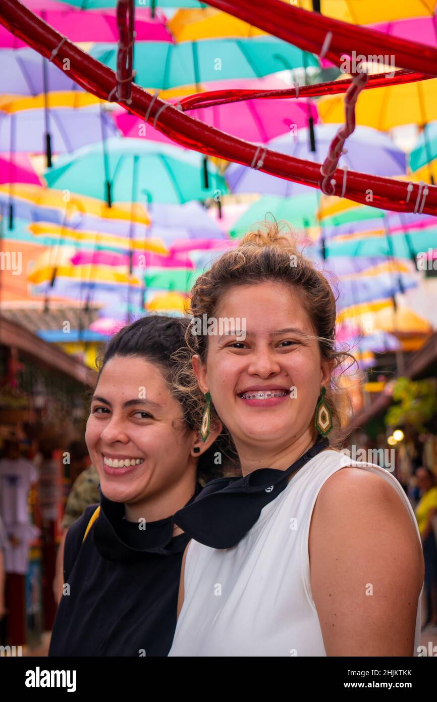 Guatape, Antioquia, Colombie - décembre 8 2021: Les femmes amis posent et regardent la caméra dans la rue des parasols colorés Banque D'Images