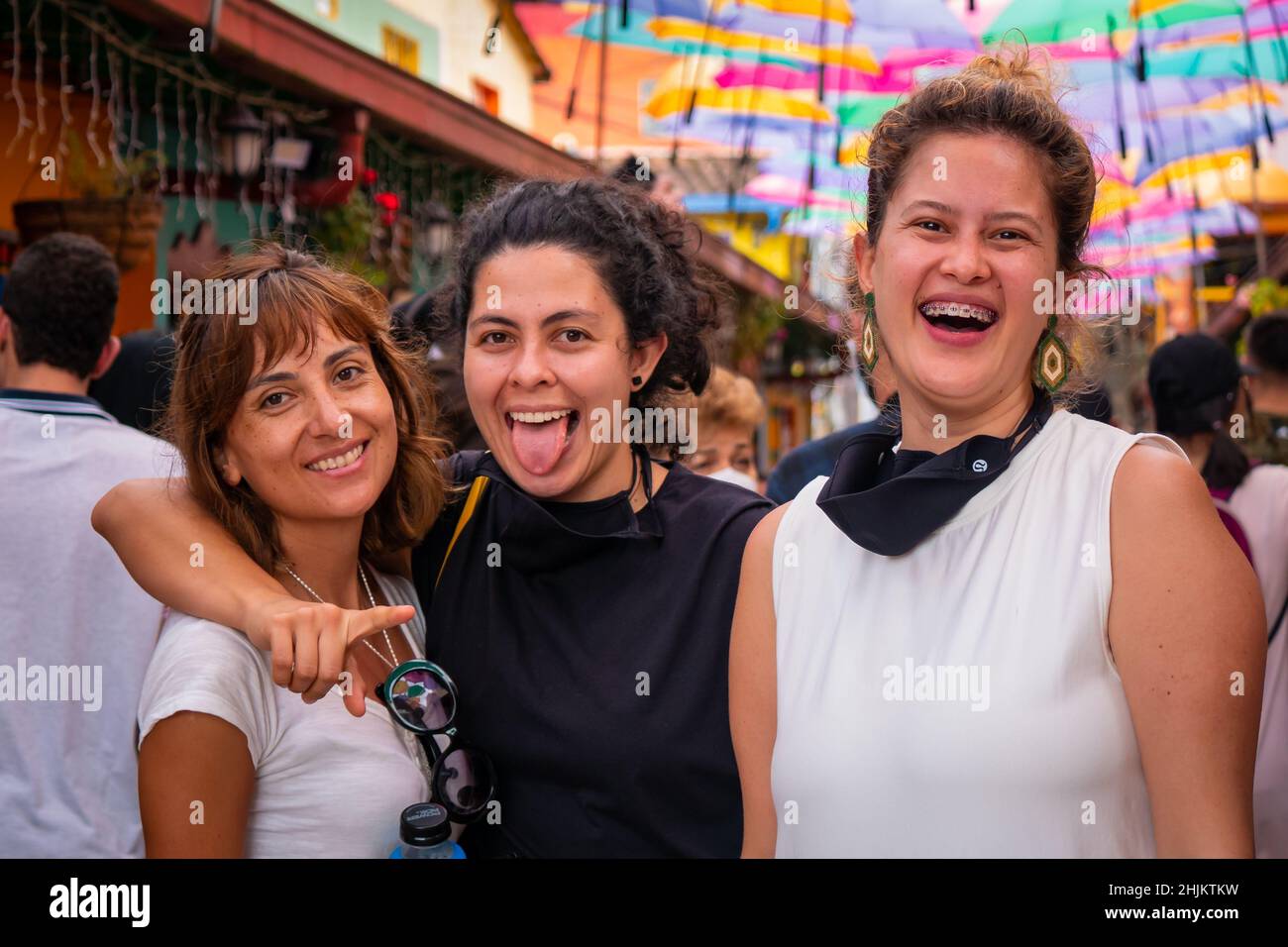 Guatape, Antioquia, Colombie - décembre 8 2021: Les femmes amis posent et regardent la caméra dans la rue des parasols colorés Banque D'Images