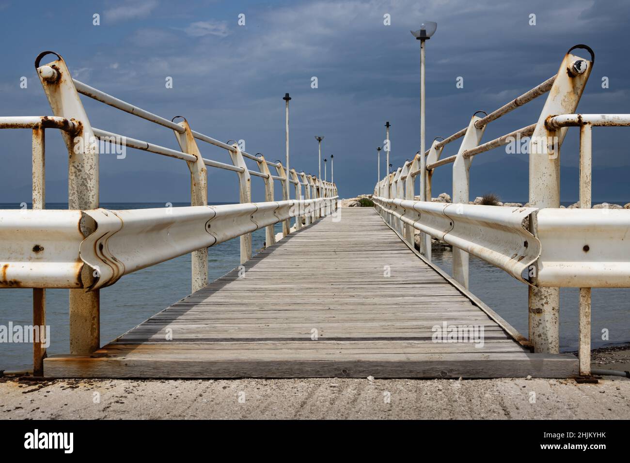 Pont en ruines vers la mer Ionienne.Garde-corps blanc rouillé, ancien chemin en bois, avec quelques pièces manquantes.Feux de route.Ciel nuageux au printemps.Roda, Corfou, G. Banque D'Images