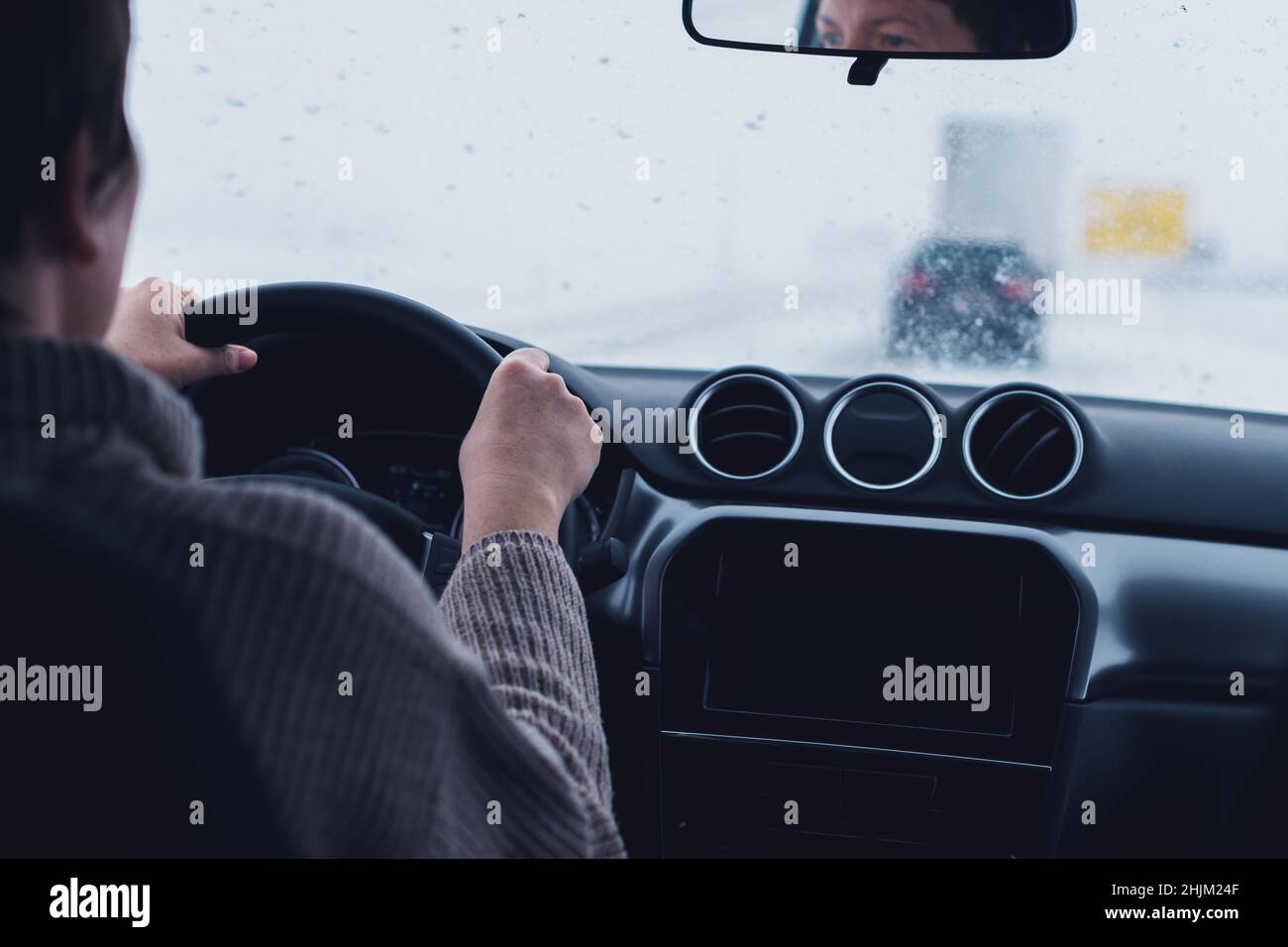 Femme conduisant une voiture dans un blizzard de neige, point de vue passager avec une attention sélective Banque D'Images