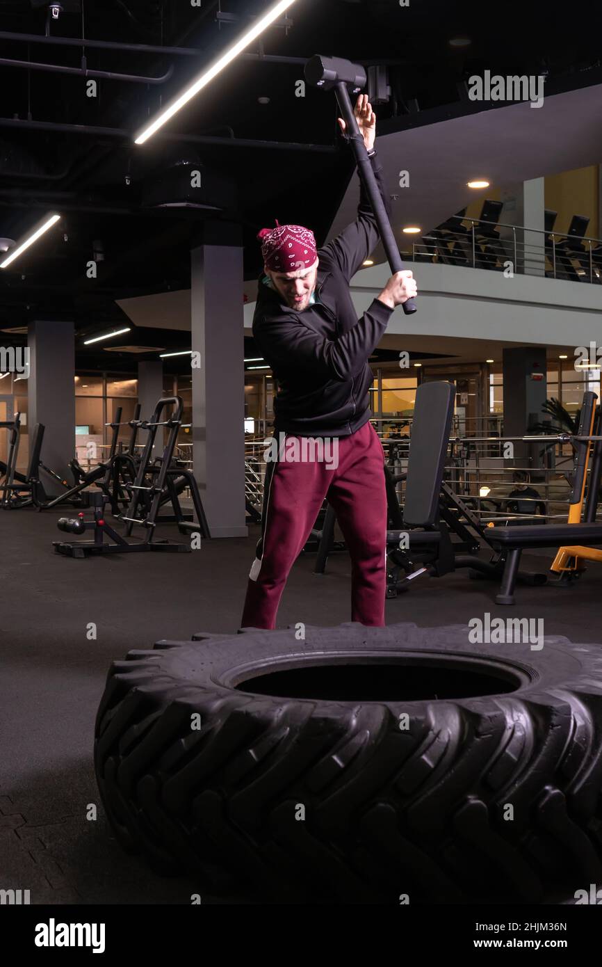Un homme frappe une roue de sledgehammer en forme physique, le concept d'un style de vie sain masculin sledgehammer actif frapper sport, pour l'exercice de force pour adulte pour Banque D'Images