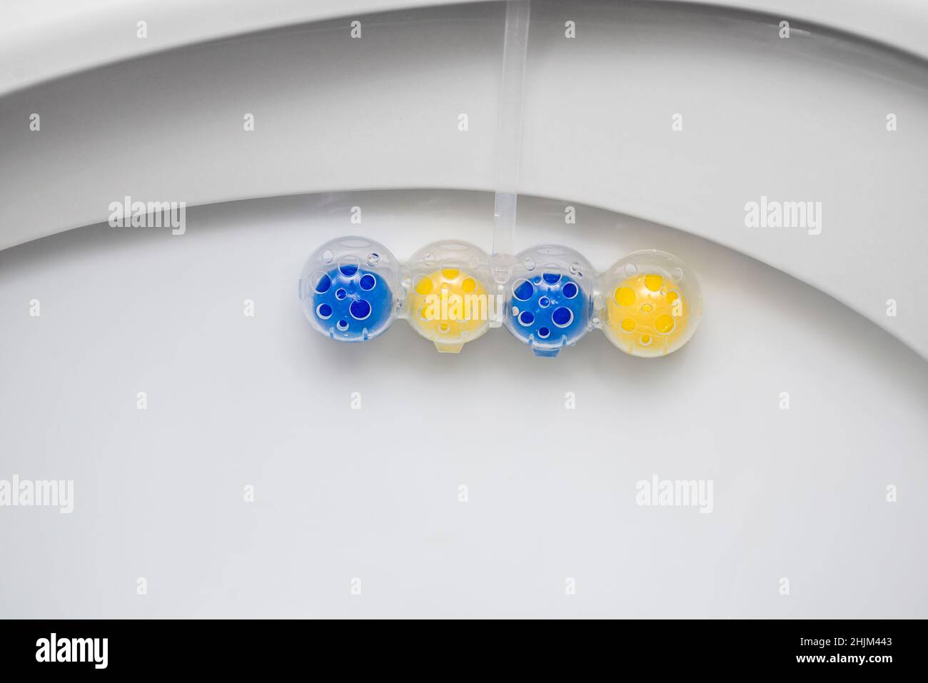 Nettoyez le bol des toilettes avec des boules nettoyantes et rafraîchissantes.Boules multicolores de nettoyant pour cuvette de toilette. Banque D'Images
