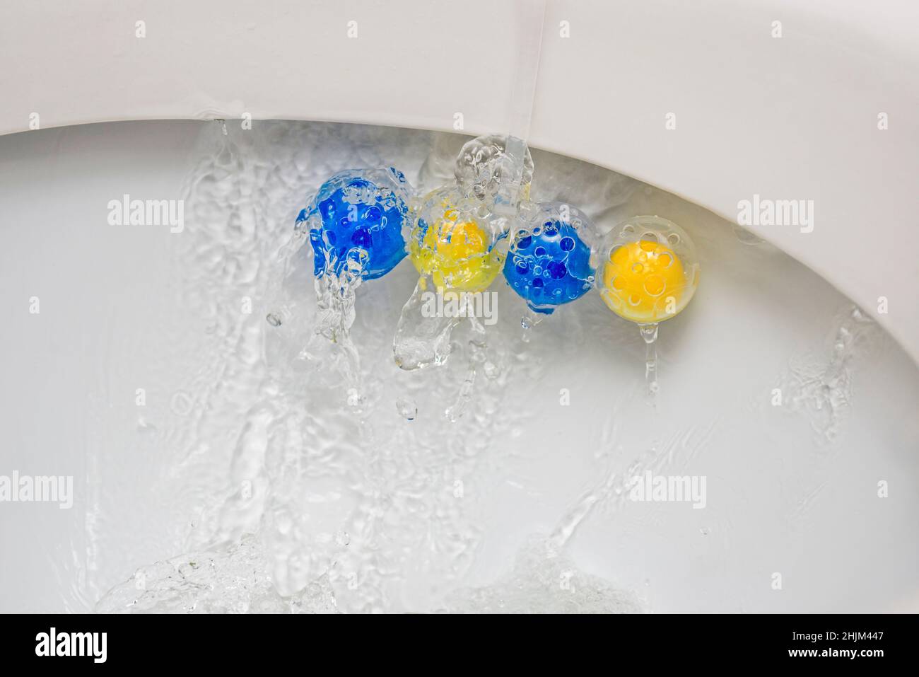 Nettoyez le bol des toilettes avec des boules nettoyantes et rafraîchissantes.Boules multicolores de nettoyant pour cuvette de toilette. Banque D'Images