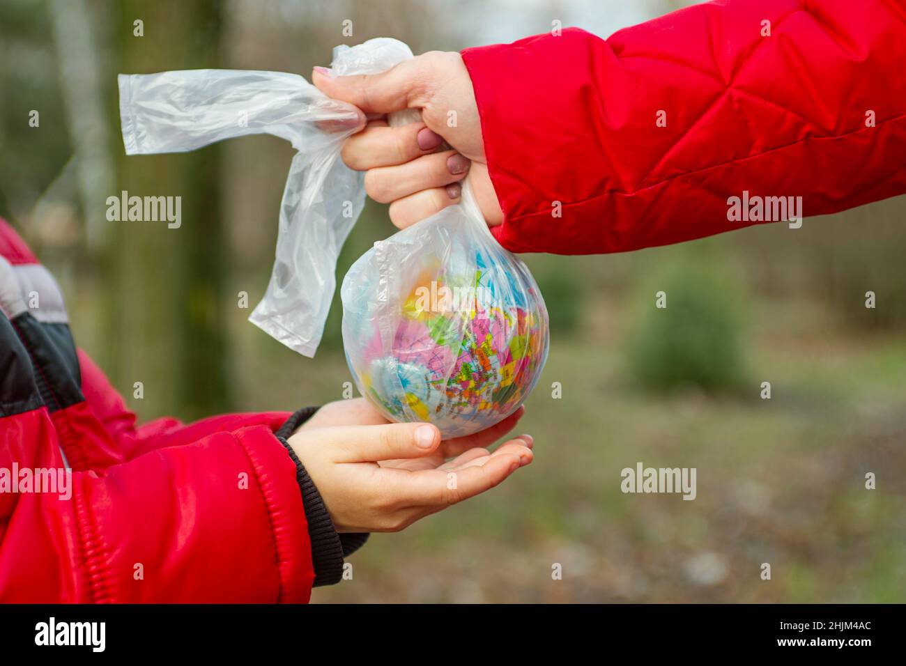 Main d'un petit enfant qui atteint pour prendre un globe dans un sac en plastique d'un adulte afin qu'il puisse prendre soin de la terre pour son avenir.Sauver la terre.Mau Banque D'Images