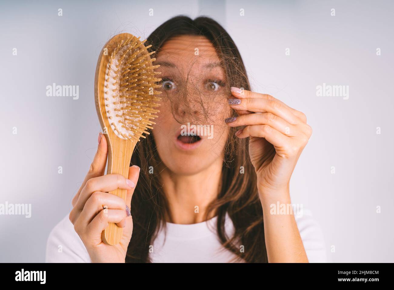 Jeune femme choquée à cause du problème de perte de cheveux.Femme tenant une brosse à cheveux et montrant des cheveux endommagés.Mauvais cheveux tomber Banque D'Images