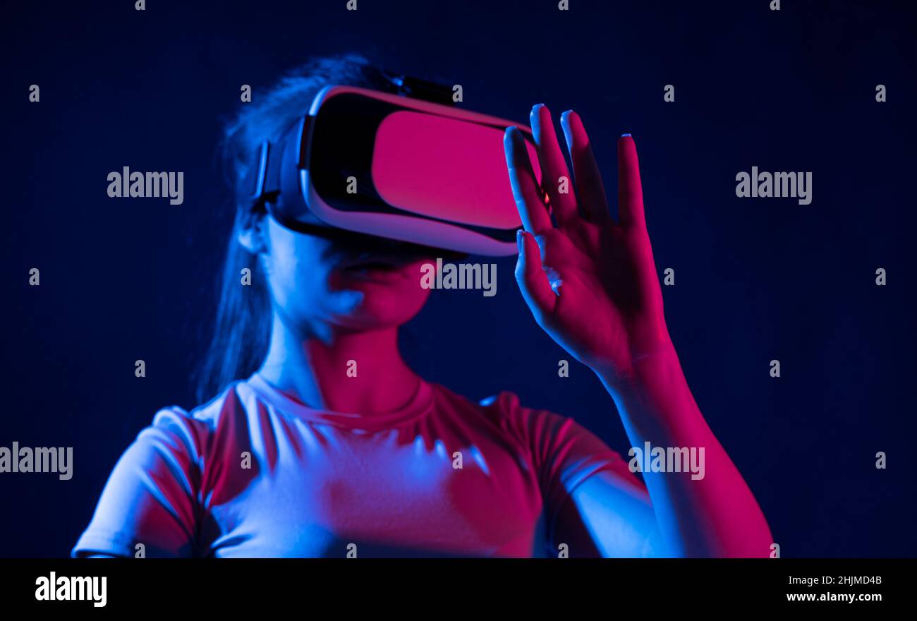 Femme dans un casque VR essayant de toucher des objets en réalité virtuelle. Banque D'Images
