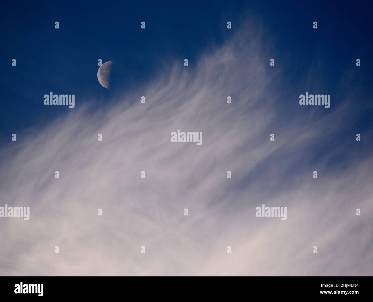 Une lune du dernier quart, parfois appelée demi-lune, partage le ciel avec des nuages cirrus plus sages au-dessus de Santa Fe, Nouveau-Mexique. Banque D'Images