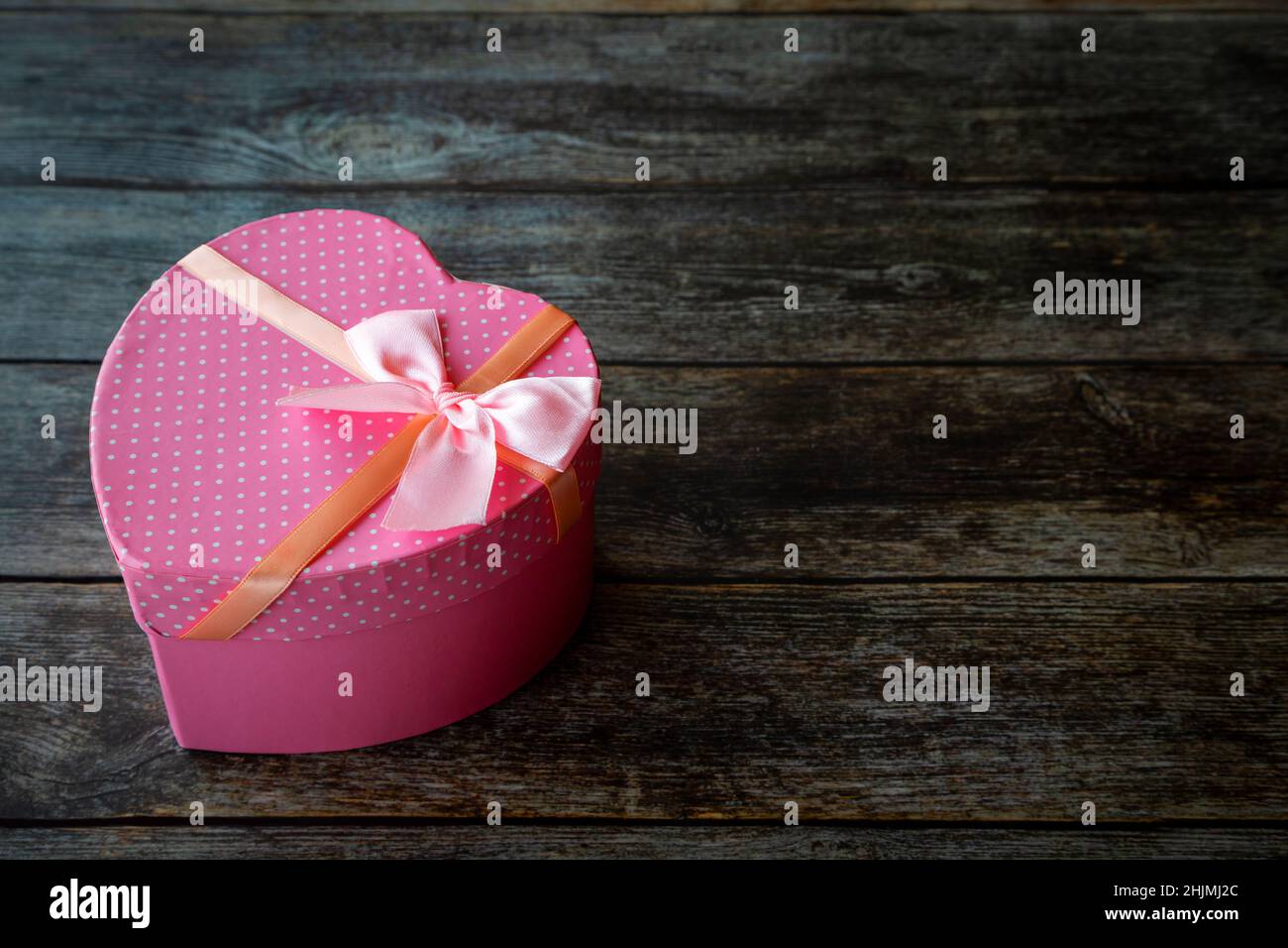 Boîte cadeau de Saint-Valentin en forme de coeur rose sur une table en bois avec espace pour les copies. Banque D'Images
