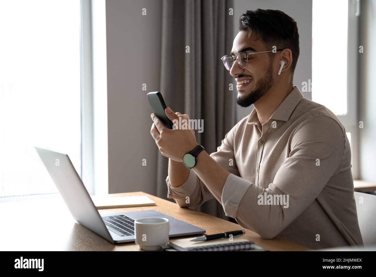Jeune homme d'affaires souriant lisant et répondant à un message sur smartphone Banque D'Images