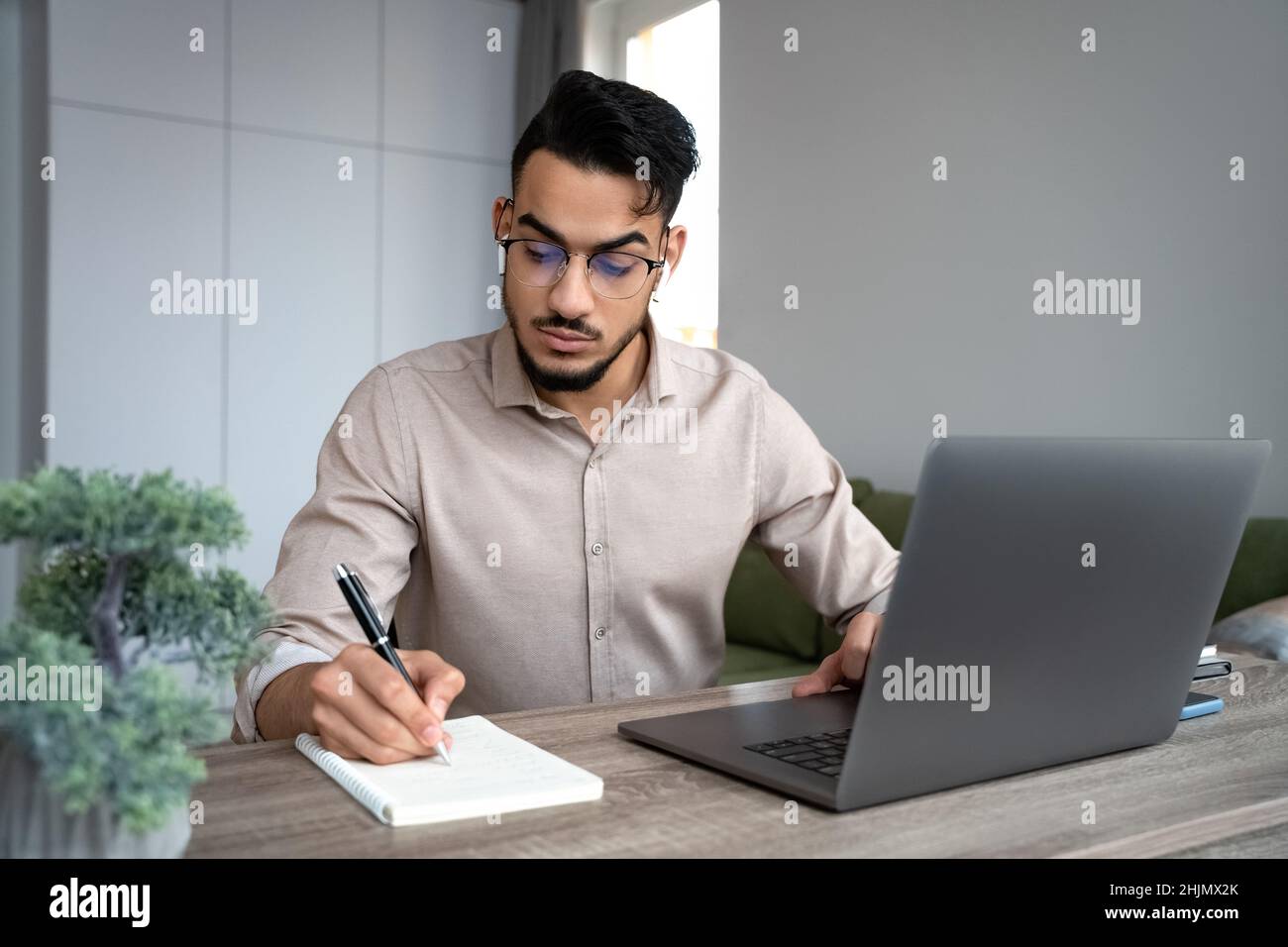 Jeune homme étudiant étudier sur un ordinateur portable en cours d'université en ligne à partir de bureau à domicile Banque D'Images