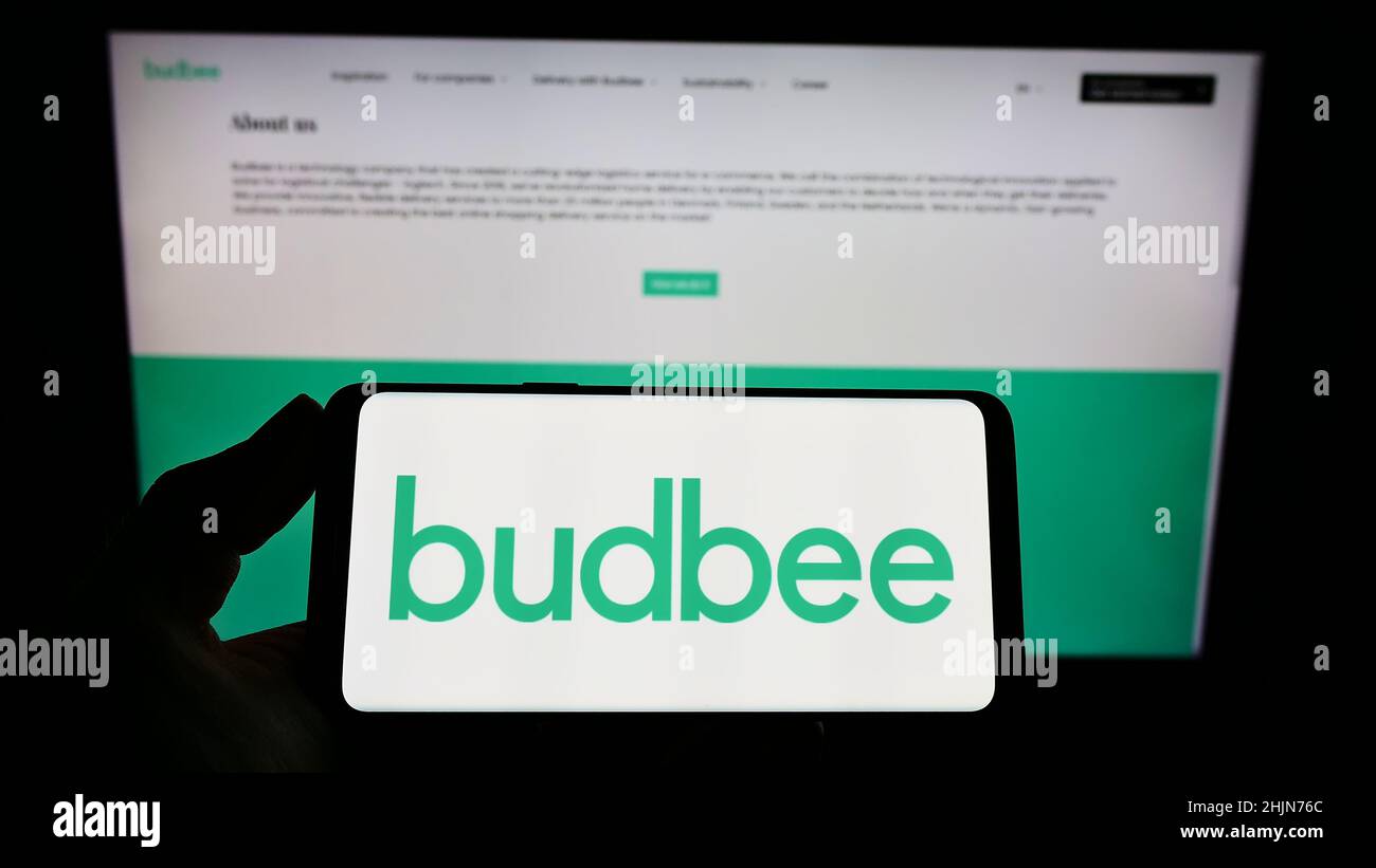 Personne tenant un smartphone avec le logo de la société suédoise de logistique Budbee AB à l'écran devant le site Web.Mise au point sur l'affichage du téléphone. Banque D'Images