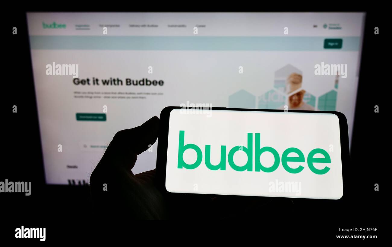 Personne tenant un téléphone portable avec le logo de la société suédoise de logistique Budbee AB sur l'écran en face de la page Web d'affaires.Mise au point sur l'affichage du téléphone. Banque D'Images