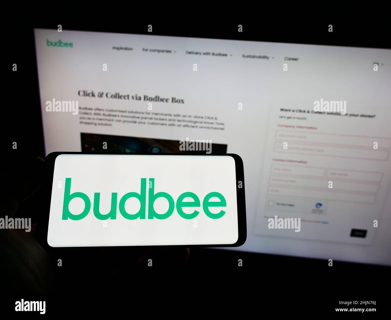 Personne tenant le téléphone portable avec le logo de la société suédoise de logistique Budbee AB sur l'écran en face de la page web d'affaires.Mise au point sur l'affichage du téléphone. Banque D'Images